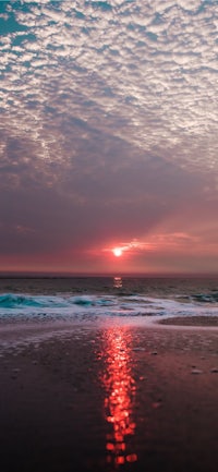 a sunset over a beach with clouds in the background