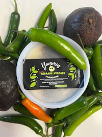 a bowl of guacamole surrounded by peppers and avocados