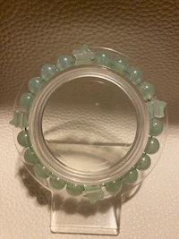 a clear glass holder with green beads on it