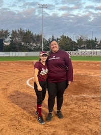 two girls standing on a softball field