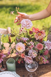 a woman is putting flowers in a vase