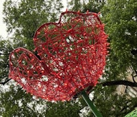 a large red flower sculpture in the middle of a park