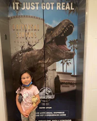 a little girl standing in front of a poster advertising jurassic park