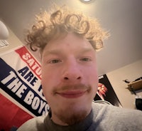 a man with curly hair is taking a selfie