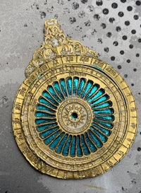 a gold and turquoise clock on a piece of metal