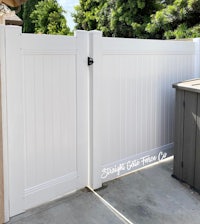 a white fence in a backyard with a trash can