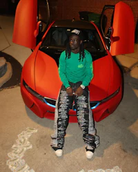 a man sitting in front of a red sports car