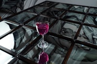 a glass of purple liquid on a glass table