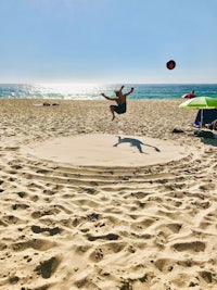a man jumping over a frisbee in the sand