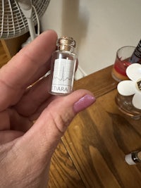 a person holding a small bottle of perfume