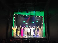 a group of people on stage with their hands up