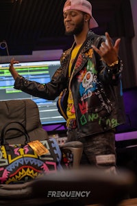 a man wearing a jacket and hat in front of a computer