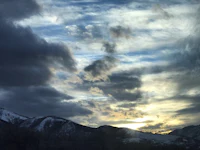 the sun is setting over a snowy mountain range