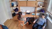 two women sitting at a desk in a room
