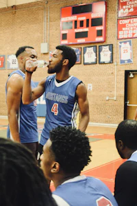a group of basketball players drinking from a water bottle