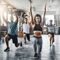 a group of people doing squats in a gym