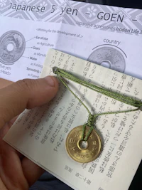 a person is holding a japanese coin