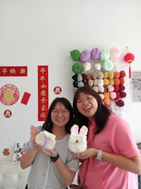 two women posing for a photo in a room full of yarn