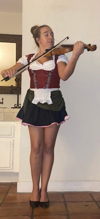a girl in a bavarian costume playing a violin