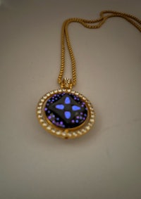 a pendant with a blue stone and pearls on a gold chain