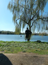 a man standing next to a tree near a body of water