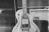 a black and white photo of a guitar in front of a amp