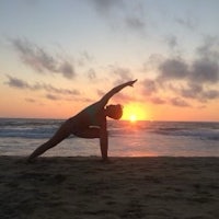 a woman practicing yoga on the beach at sunset