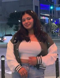 a young woman wearing a varsity jacket and jeans