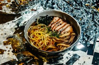 a bowl of ramen with meat and noodles on a table