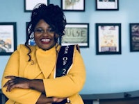 a woman wearing a yellow jacket and a sash
