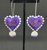 a pair of purple heart shaped earrings with pearls
