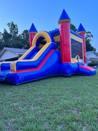 a colorful inflatable bouncer with a slide in the background