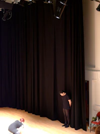 a person standing on a stage in front of a black curtain