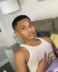 a young man in a tank top sitting on a couch