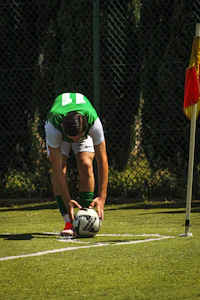 a man bending down to pick up a soccer ball