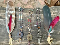 a group of feathers, beads and feathers on a piece of wood