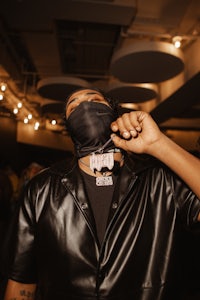 a man in a black leather jacket with a black mask on his face