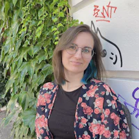 a woman wearing glasses and a floral shirt is sitting in front of a wall