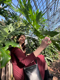 a woman sitting on a bench in a greenhouse
