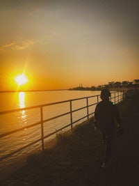 a person riding a skateboard near a body of water at sunset