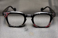 a pair of glasses with red and black crystals on them