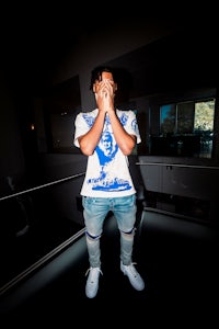 a man in a white t - shirt covering his face