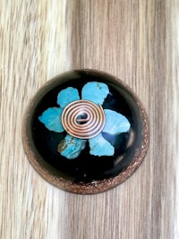 a black and turquoise flower on a wooden surface