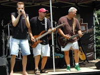 a group of men standing on stage with guitars