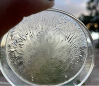 a person holding up a glass of water with frost on it