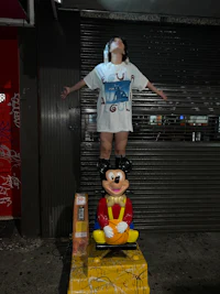 a person standing next to a mickey mouse statue