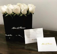 white roses in a black gift box with a card