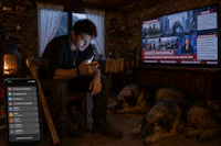 a man is sitting in front of a tv with two dogs in front of him