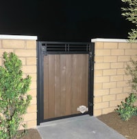 a wooden gate at night with bushes and plants