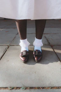 a woman wearing a white dress and brown shoes